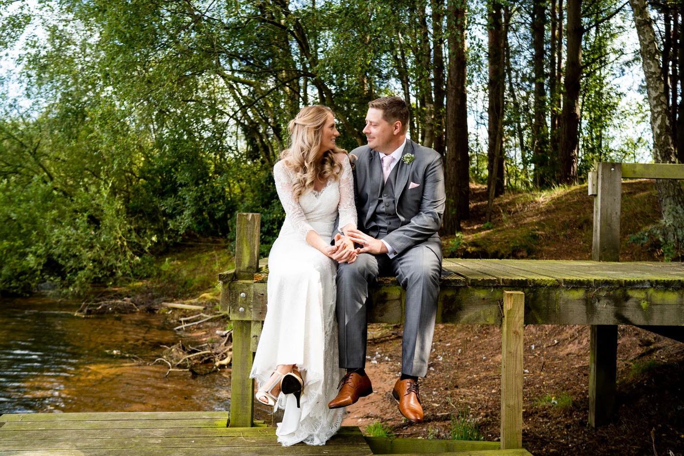 A wedding couple sitting beside a woodland stream